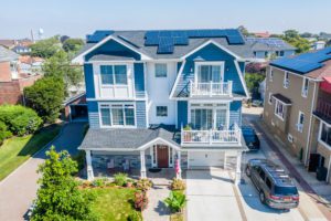 A three-story house on Long Island has solar panels on the roof so it may use solar energy. 