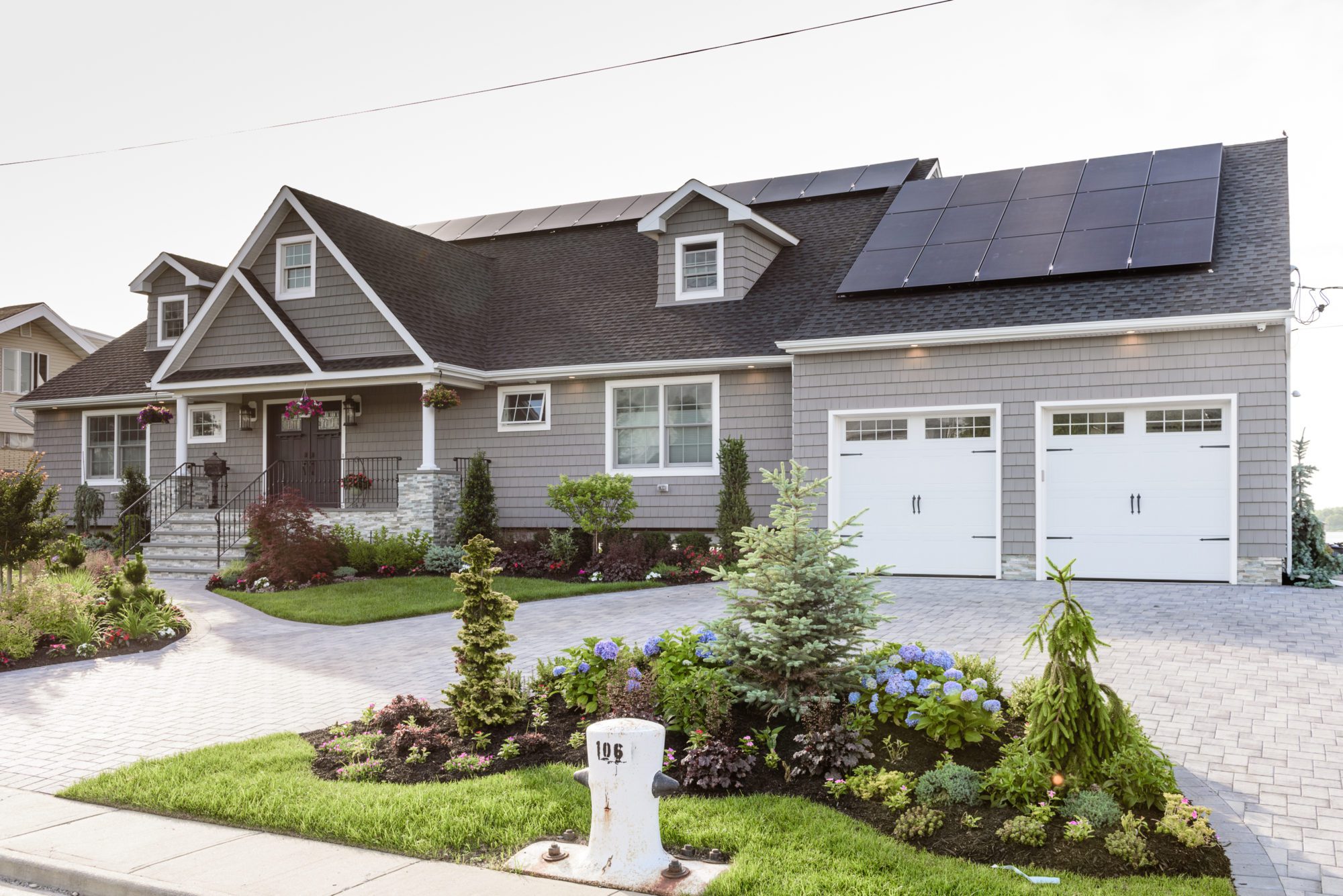 Gray single family house in Long Island with solar panels installed on the roof.